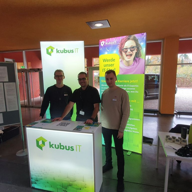 3 Mitarbeiter stehen am Messestand und schauen in die Kamera