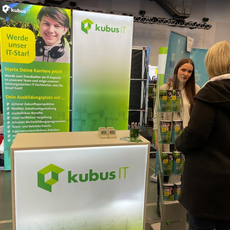 Eine Mitarbeiterin der kubus IT ist am Messestand im Gespräch mit einer Frau