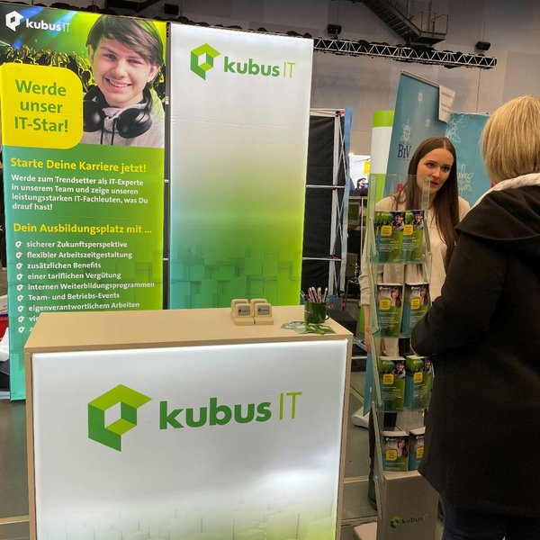 Eine Mitarbeiterin der kubus IT ist am Messestand im Gespräch mit einer Frau